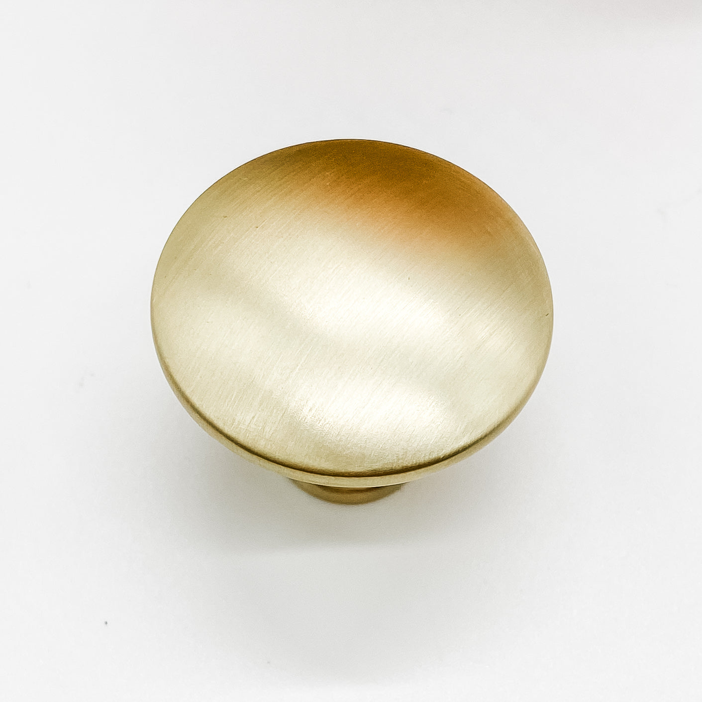 Round shaped drawer knob in brushed gold on white background - top view