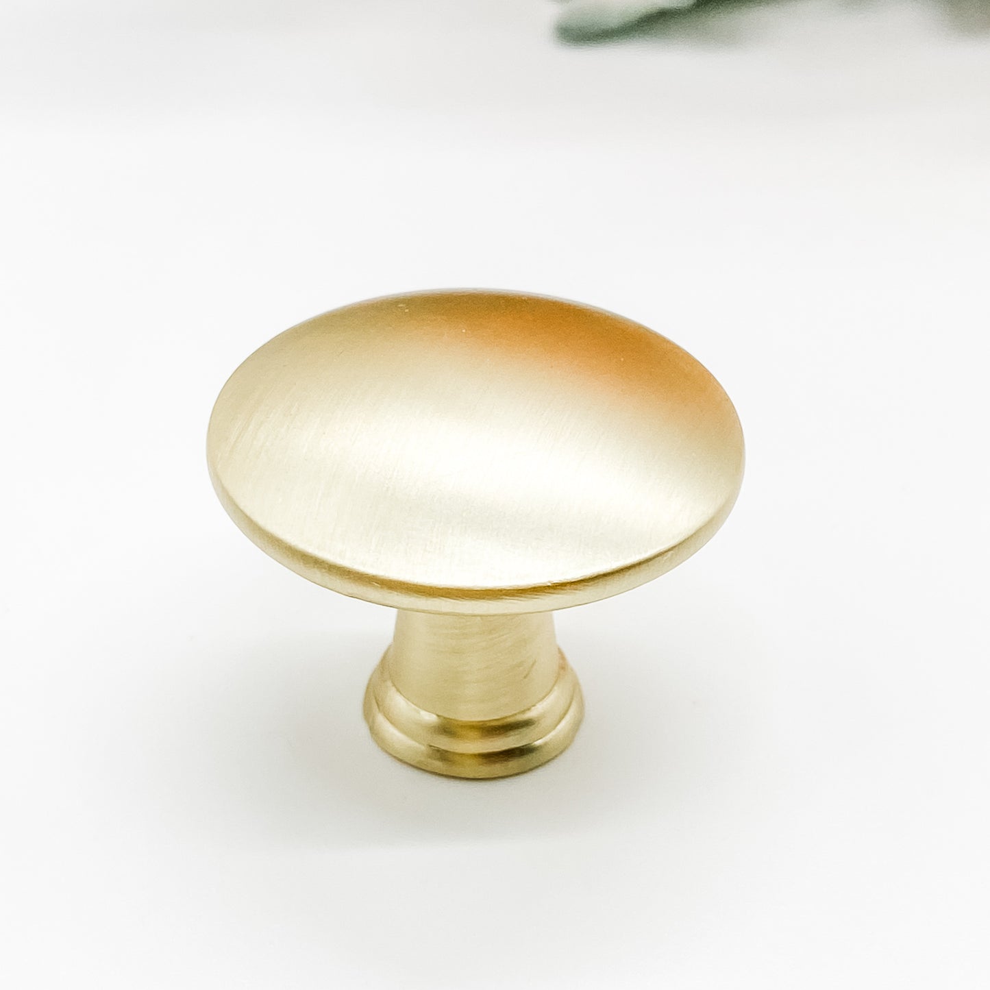 Round shaped drawer knob in brushed gold on white background