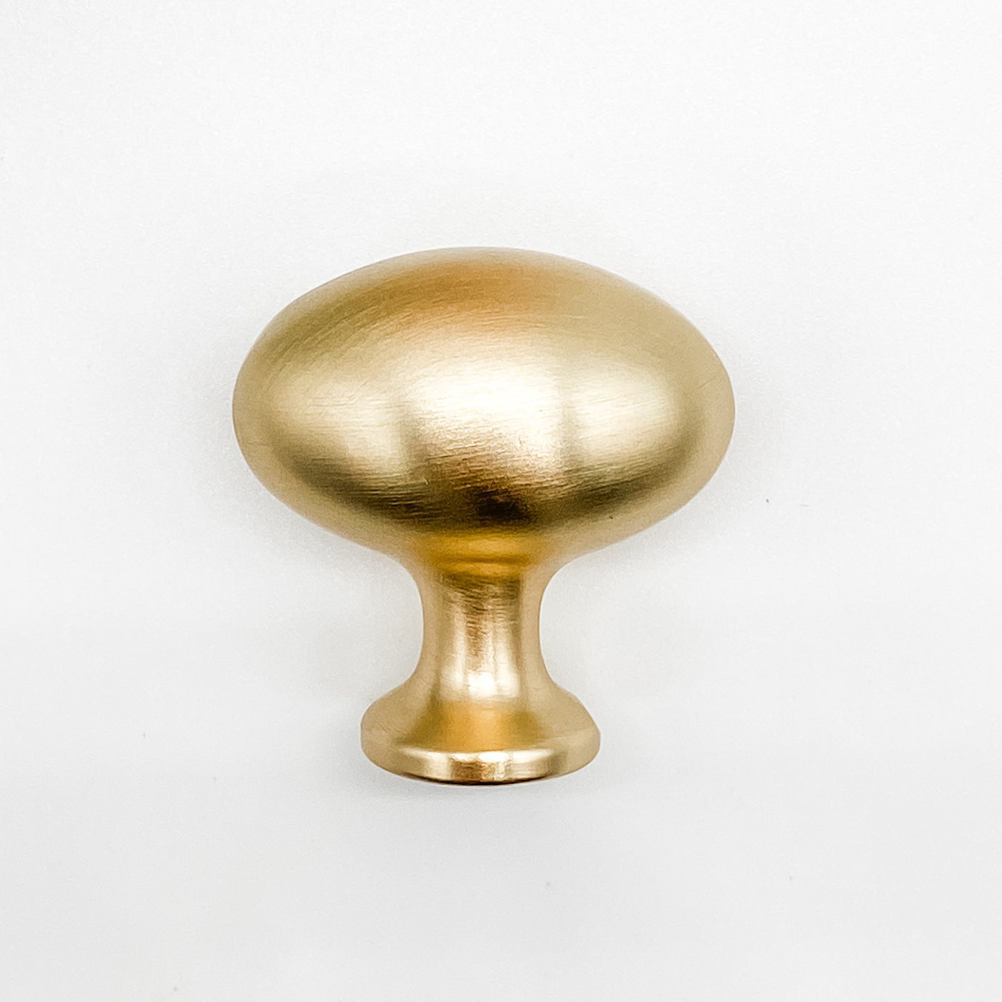 Brushed gold egg shaped cabinet knob on white background