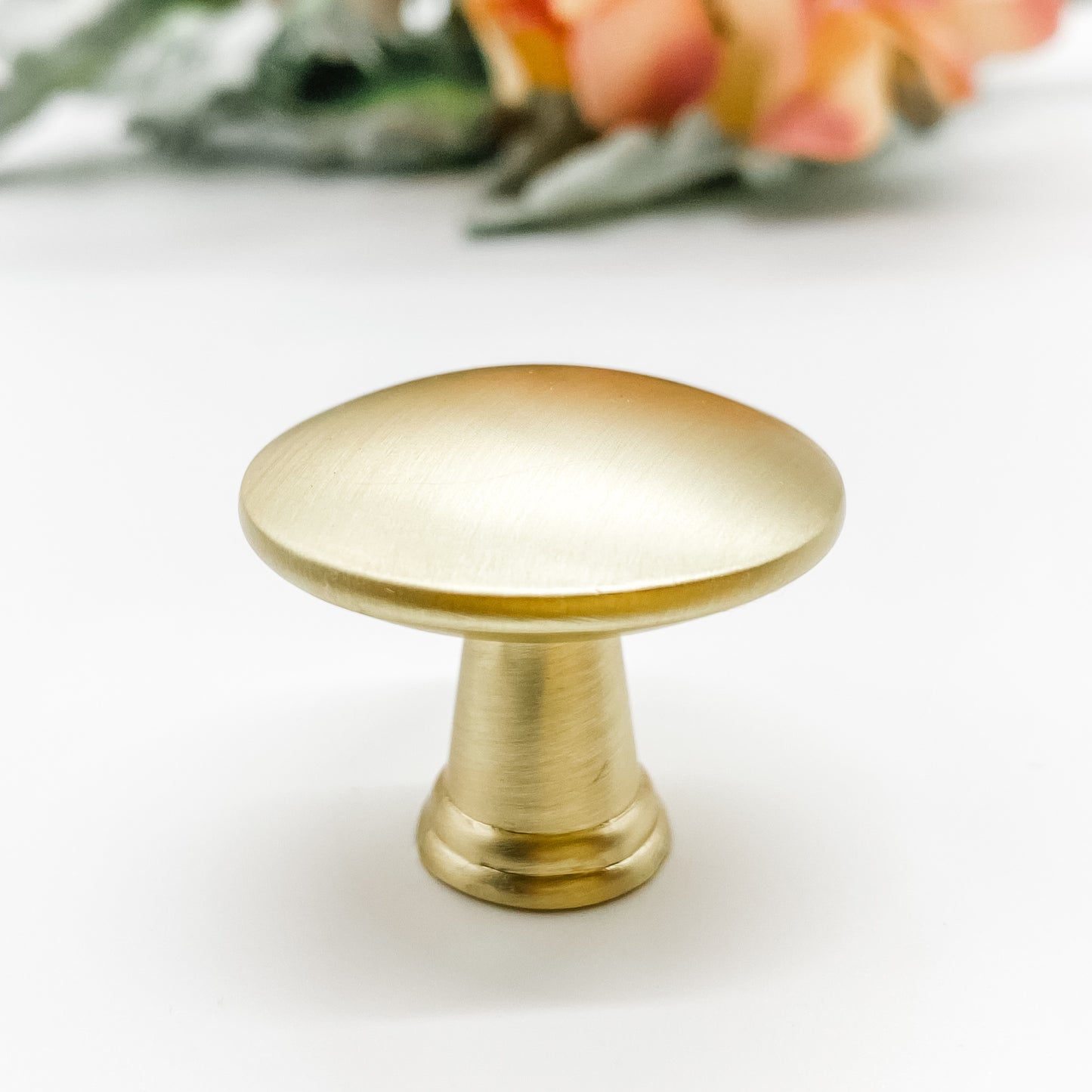 Round shaped drawer knob in brushed gold on white background side view
