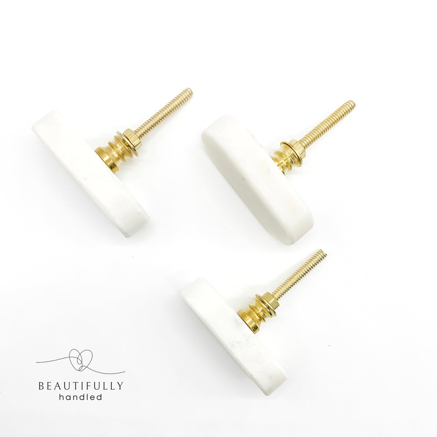 3 marble drawer handles with brass bolts on plain white background
