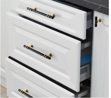 3 white kitchen drawers with black drawer handles with gold trim