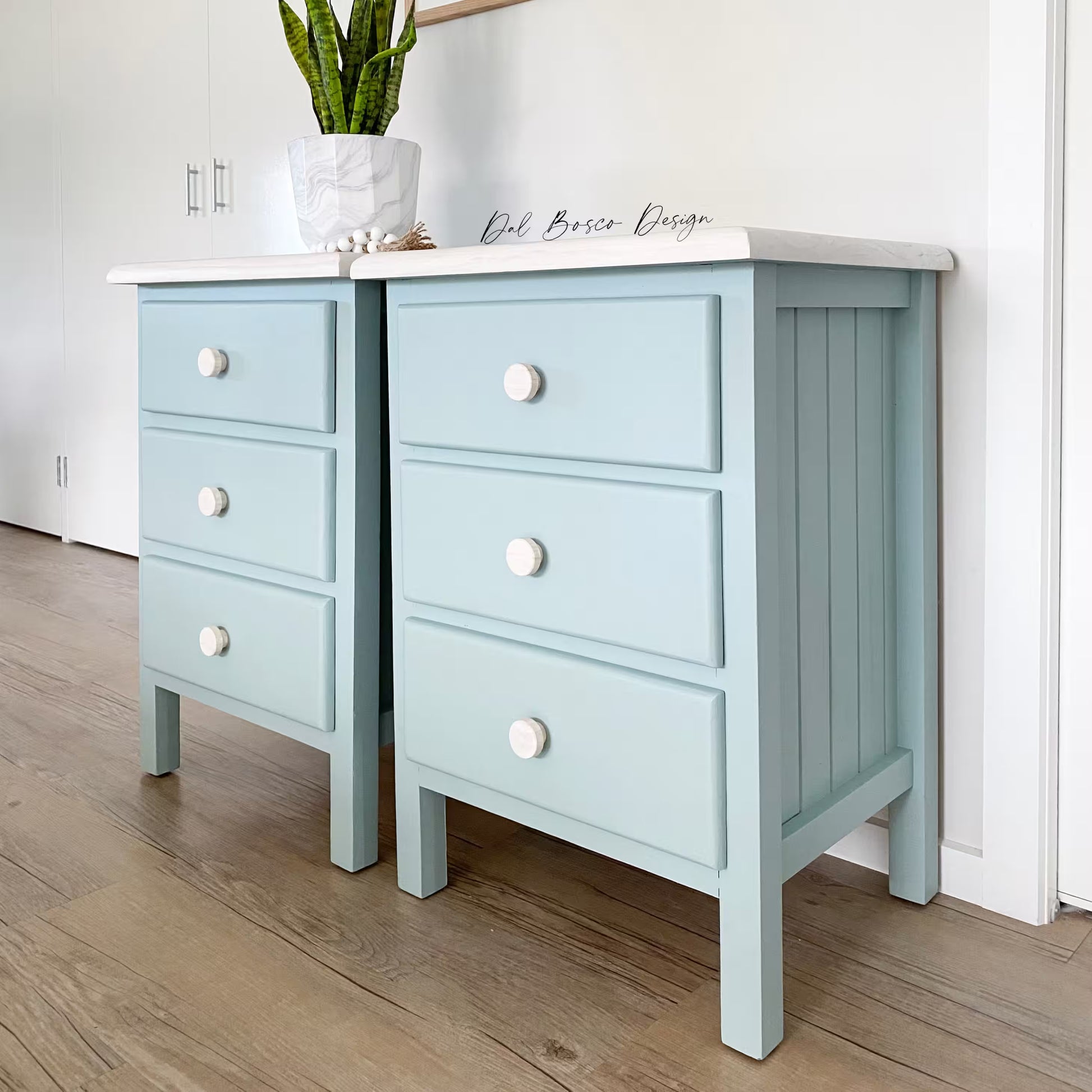 Pair of light blue nightstands with white countertops on a wooden floor.