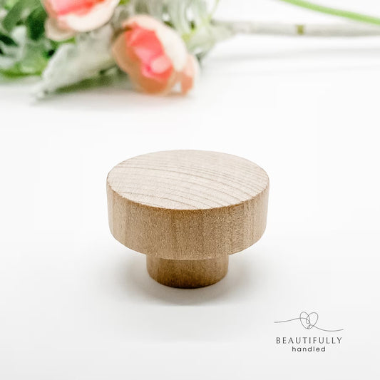 Wooden knob on a white background with a blurred floral arrangement in the background.