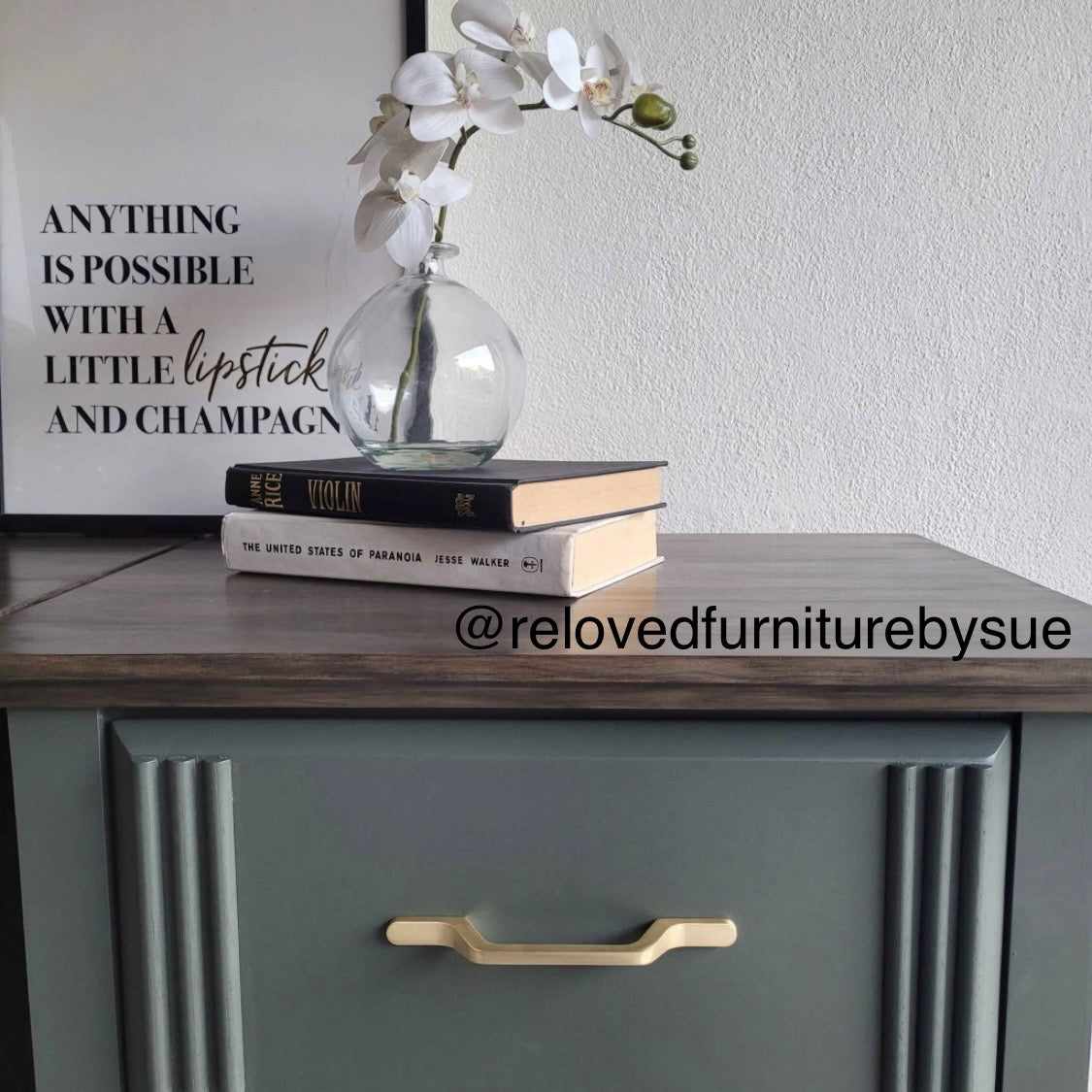 Decorative setup on a green bedside table with books, a vase with flowers, and a motivational quote. Featuring brushed gold slim handles