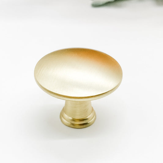Round shaped drawer knob in brushed gold on white background