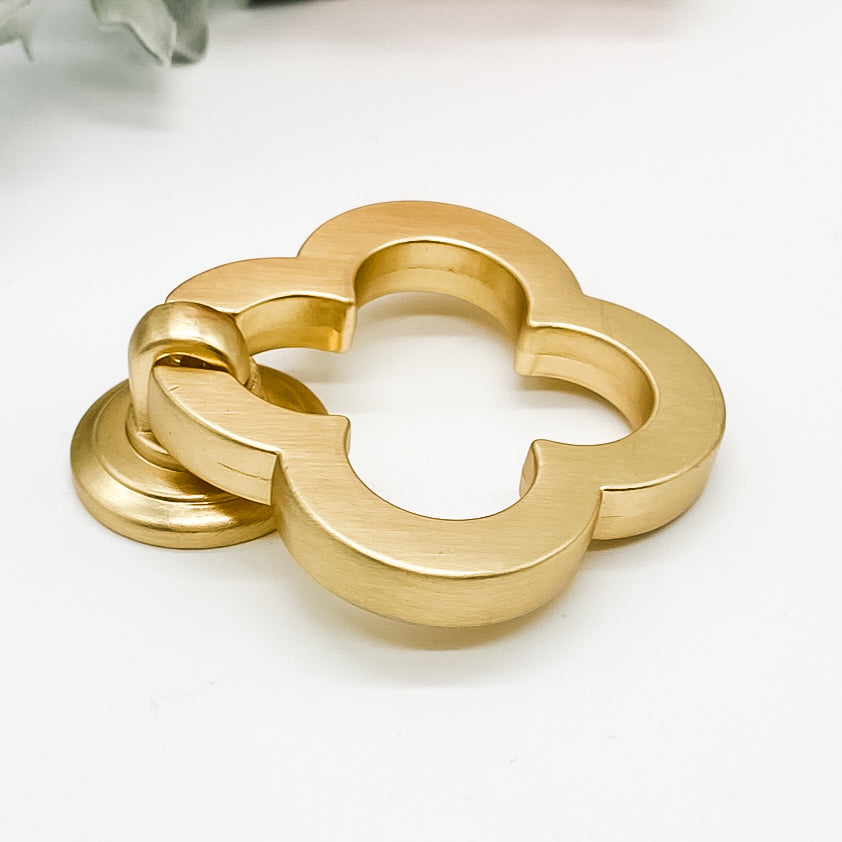 Brushed gold flower shaped clover leaf drawer handle on white background side angle