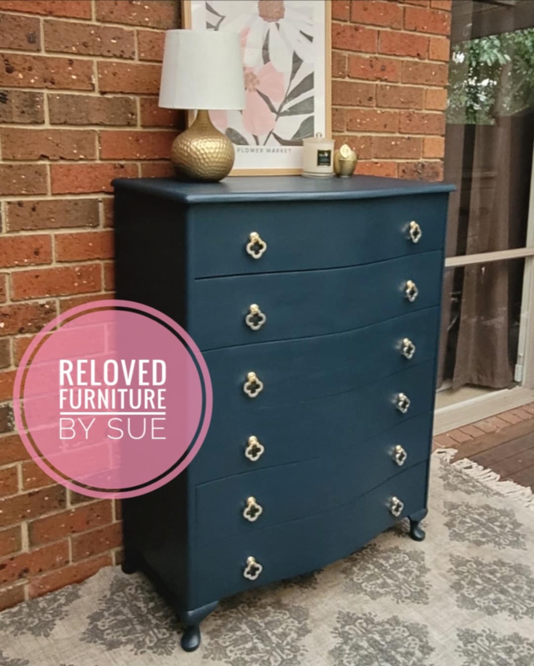 Brushed gold flower shaped clover leaf drawer handle on navy chest of drawers 