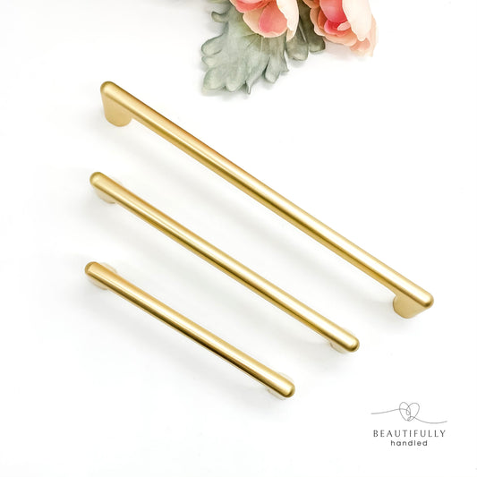 Three brushed gold cabinet handles on a white background.