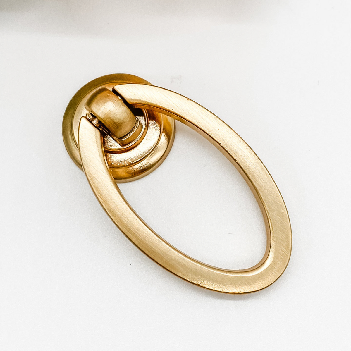 brushed gold oval shaped drop ring pull for cabinet drawers front angle on white background