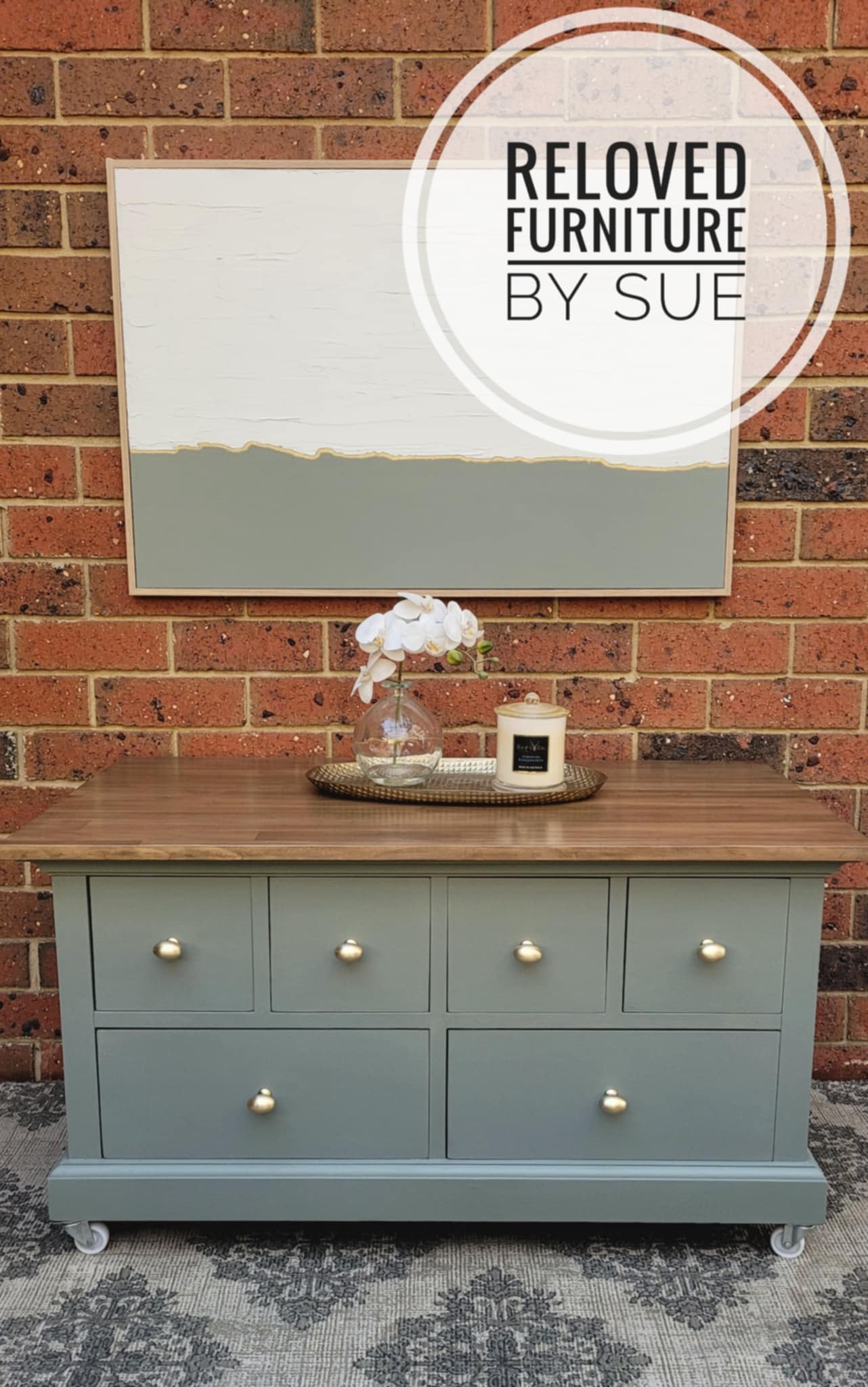 Sage green large coffee table with wooden top against a brick wall, featuring brushed gold egg shaped knobs