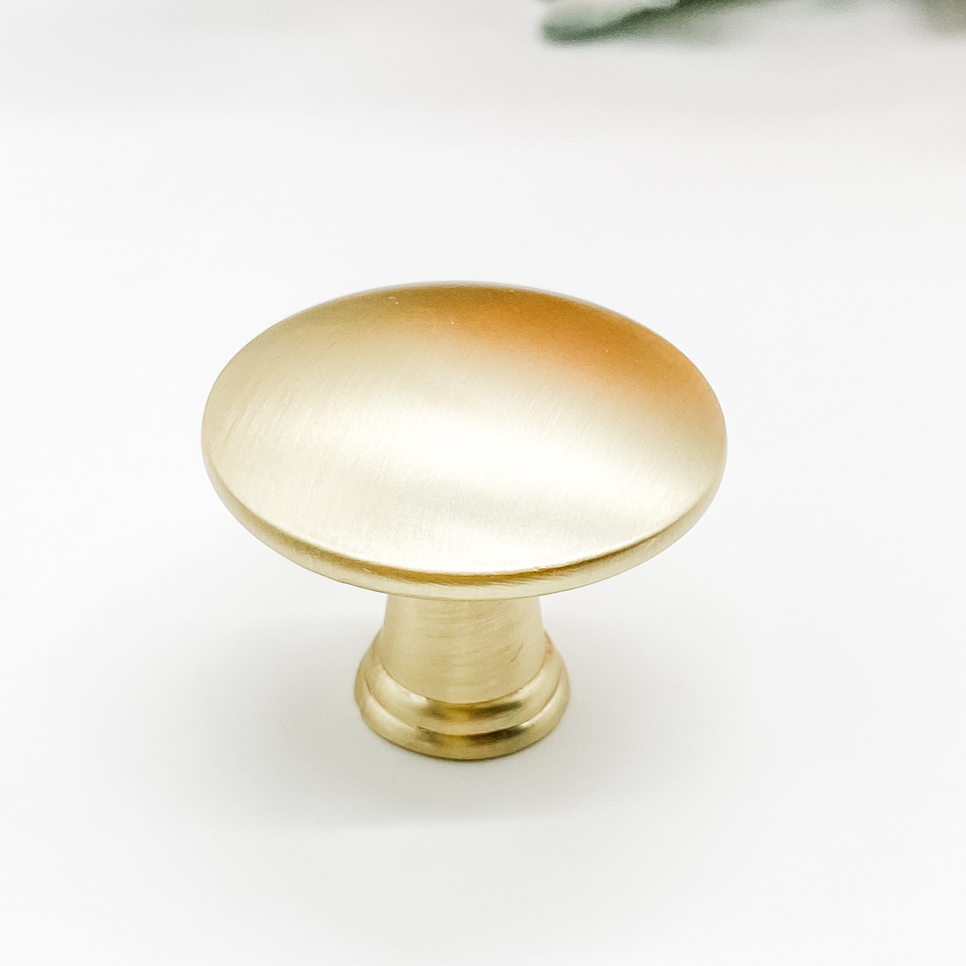 Round shaped drawer knob in brushed gold on white background