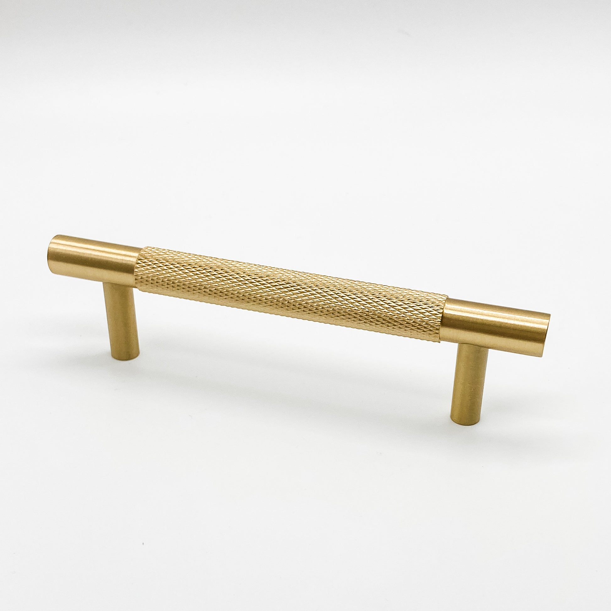 Solid brass knurled brass kitchen cabinet handle 96mm on plain white background 