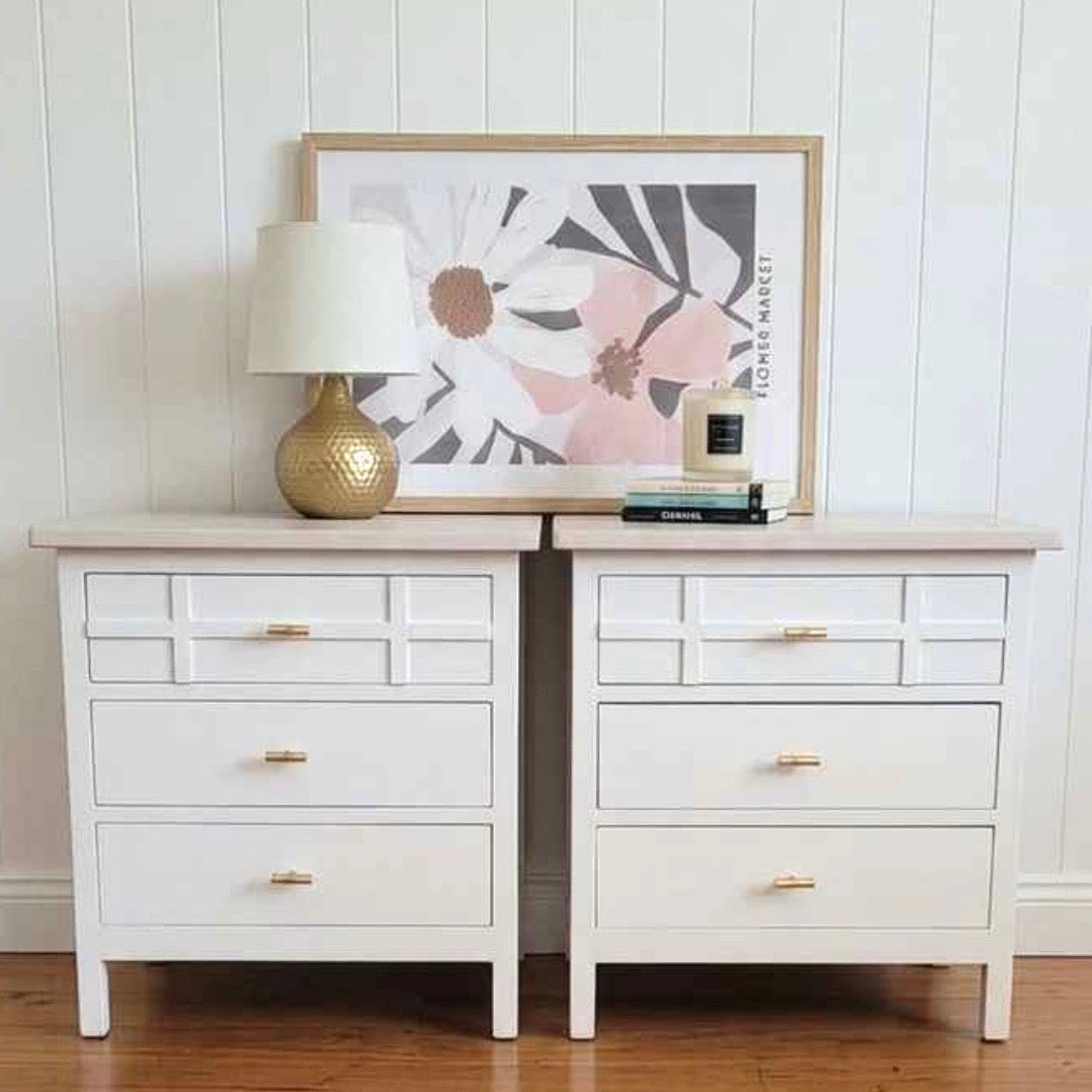 White dresser with brass handles against a white paneled wall and warm timber floorboards