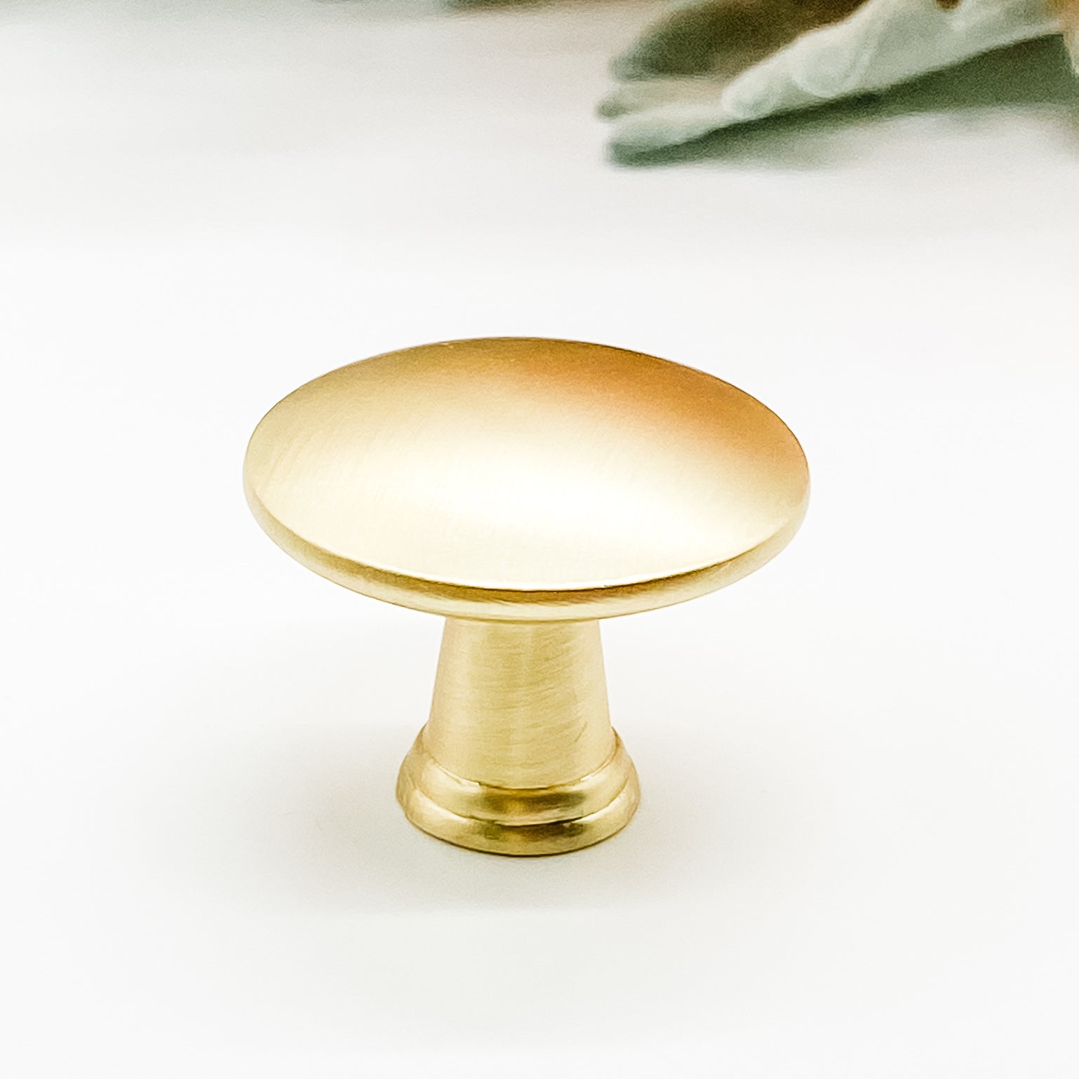 Round shaped drawer knob in brushed gold on white background side view