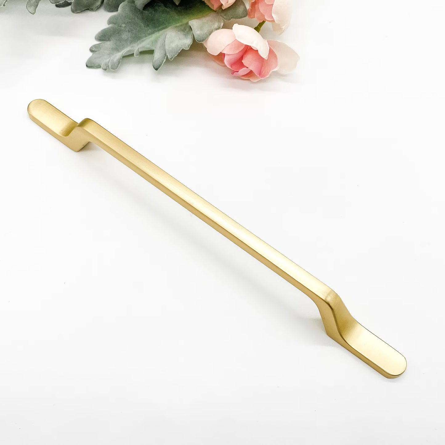 Gold slimline kitchen handle on a white background with floral elements