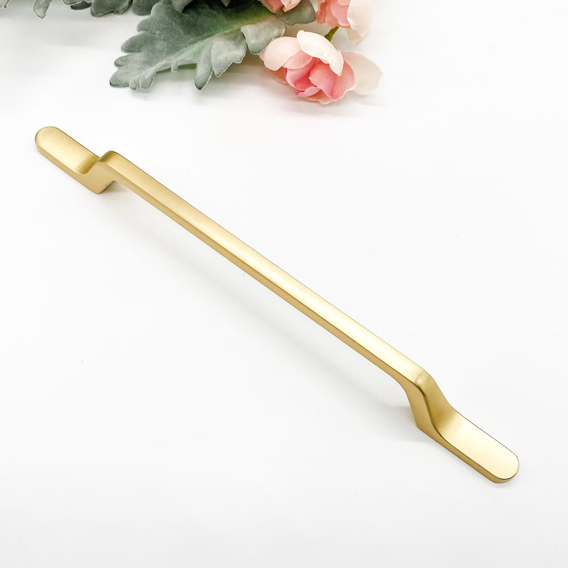 Gold slimline kitchen handle on a white background with floral elements