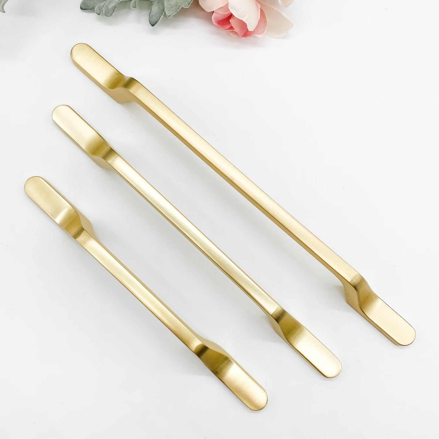 Three brushed gold kitchen handles on a white background.