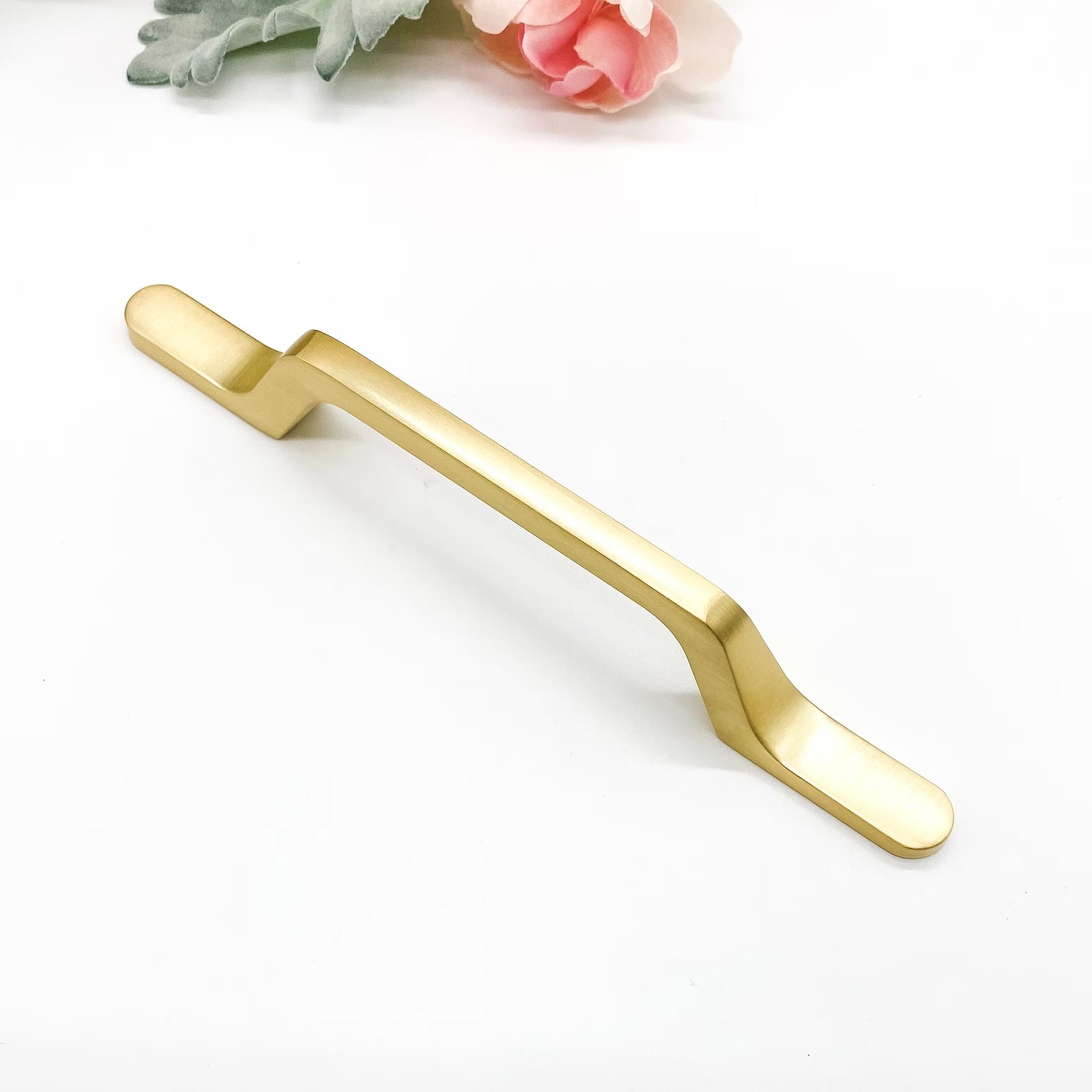 Gold cabinet handle on a white background with floral elements