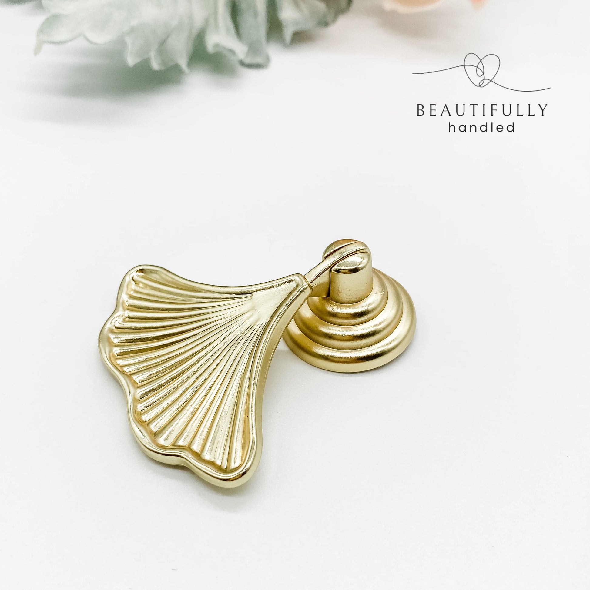 Gold leaf-shaped drawer handle on a white background 