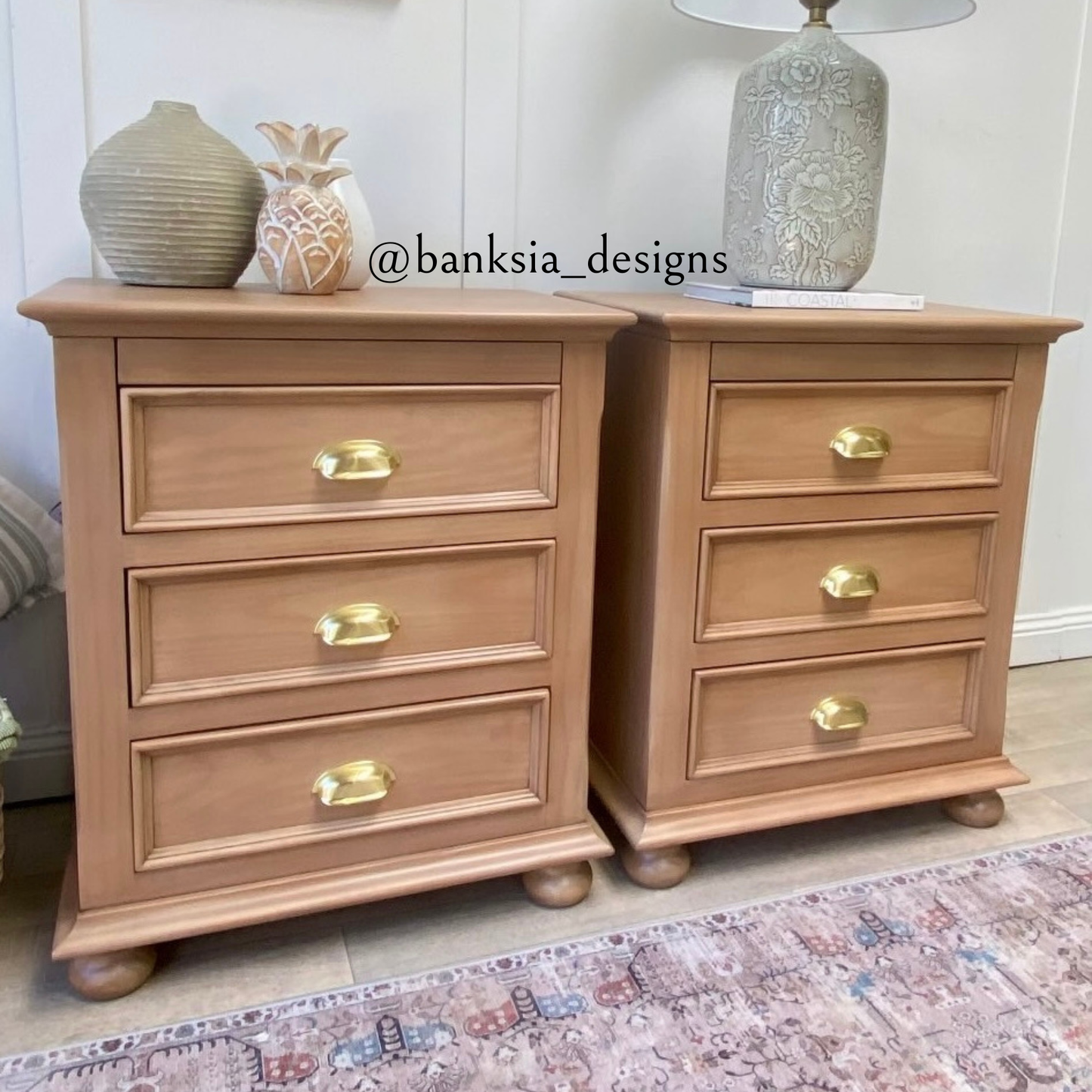 Pair of wooden nightstands with gold cup pull handles on a patterned rug.