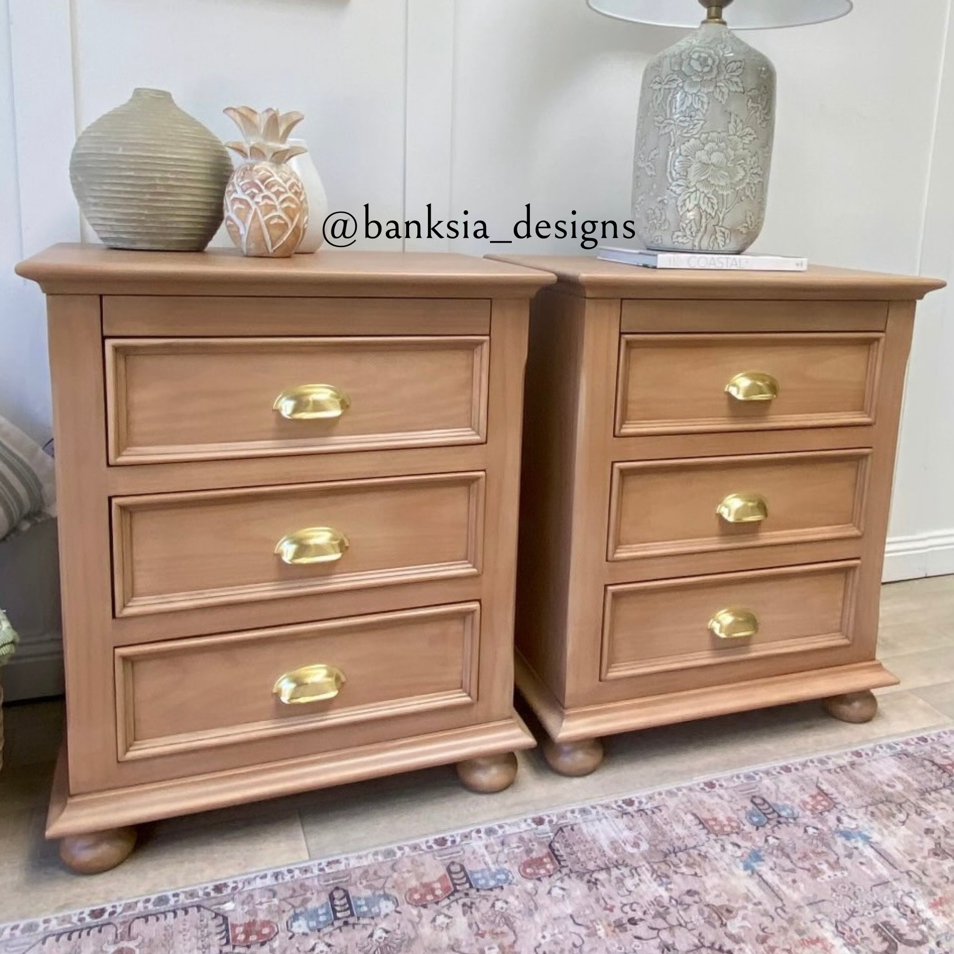 Pair of wooden nightstands with gold cup pull handles on a patterned rug.