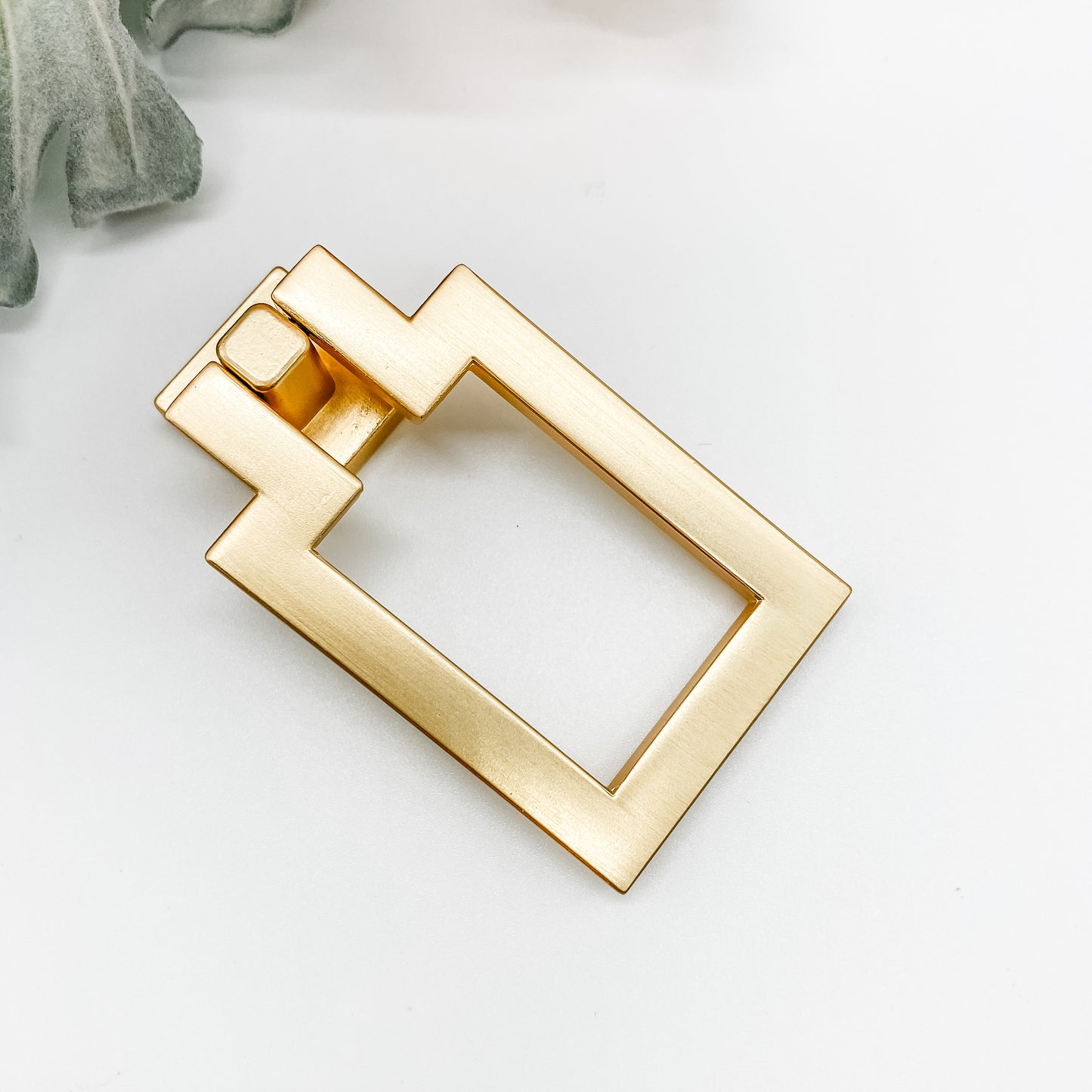 gold rectangle shaped drop pull cabinet handle on front angle on white background