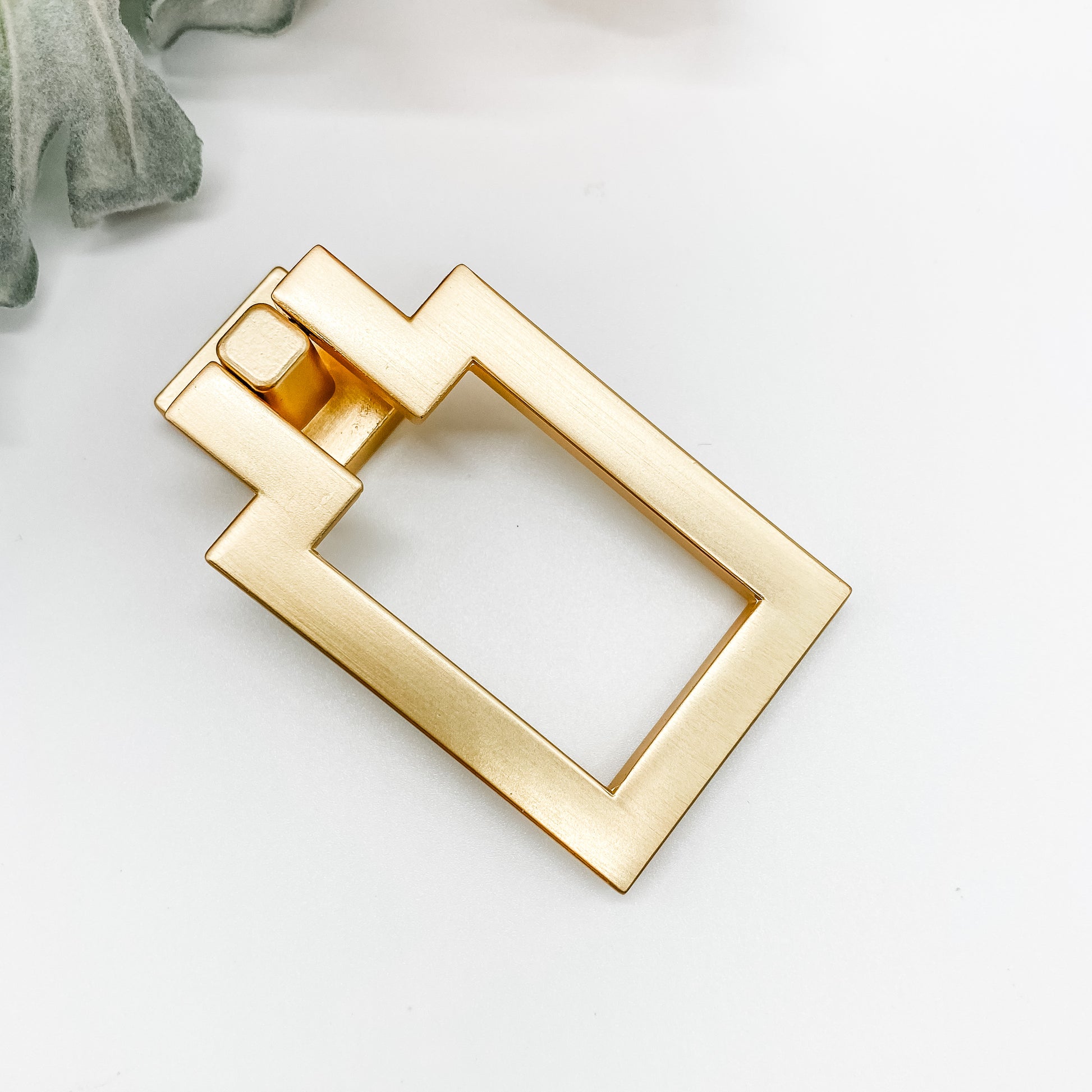 gold rectangle shaped drop pull cabinet handle on front angle on white background
