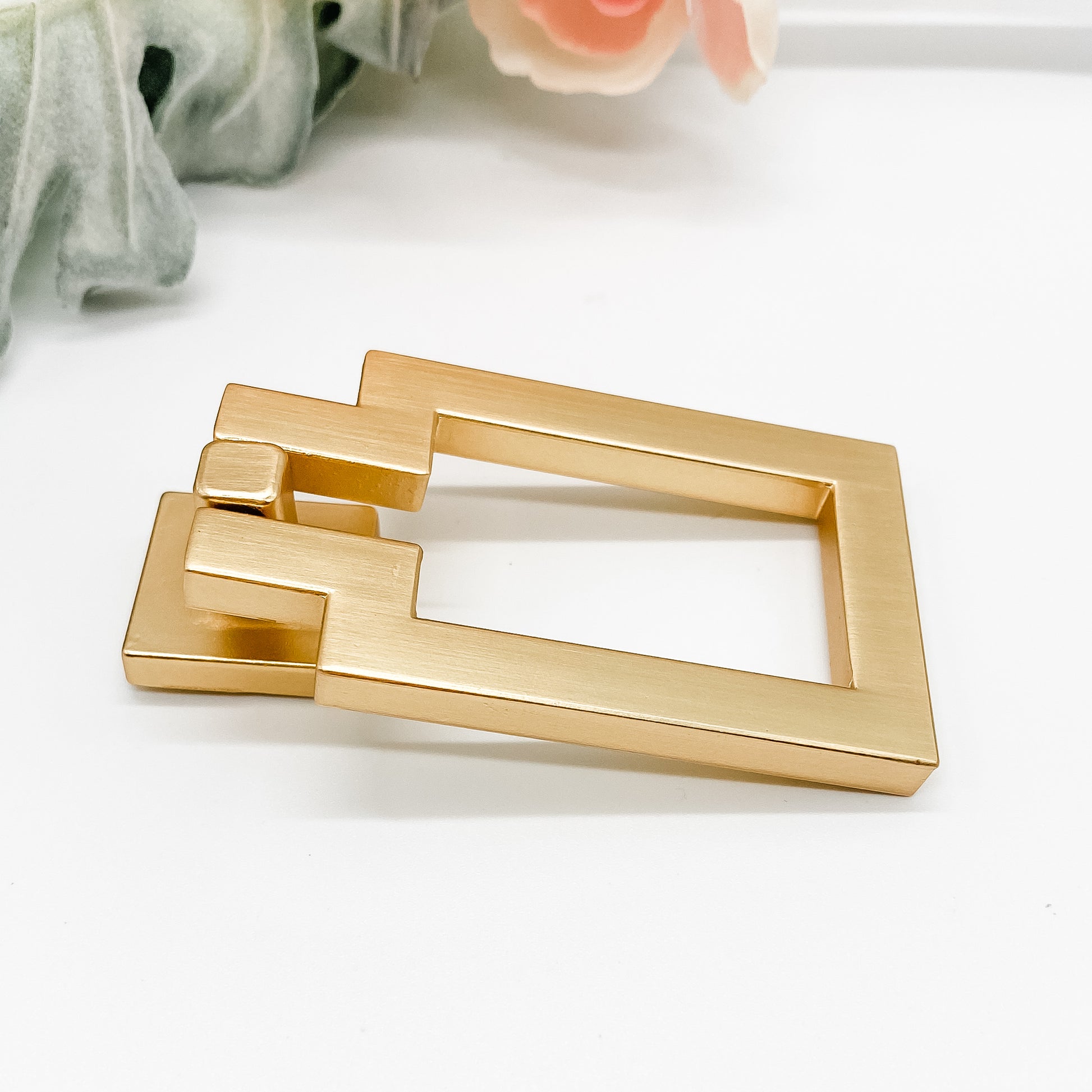 gold rectangle shaped drop pull cabinet handle on side angle on white background