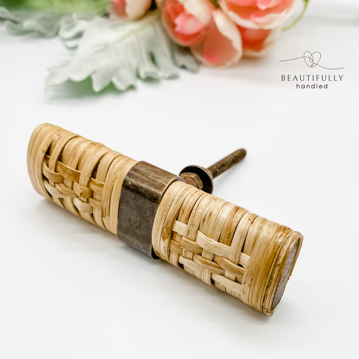 closeup of rattan tbar drawer handle on white background with flowers fainty in the background
