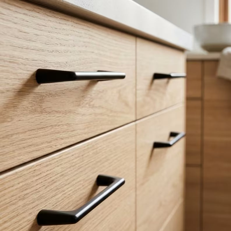Wooden cabinet with black square ended drawer handles in a kitchen setting