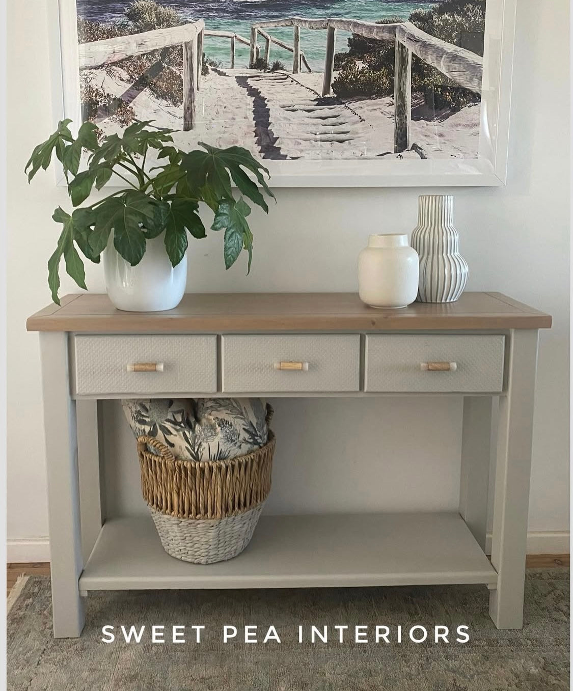 Timber and resin drawer handles on a Coastal styled hall table with pot plant, woven basket and wall mounted picture of a beach scene