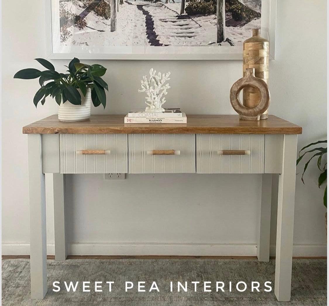 sage painted side table in coastal style featuring timber drawer handles with resin edges with pot plants and coastal decor items on top of the table