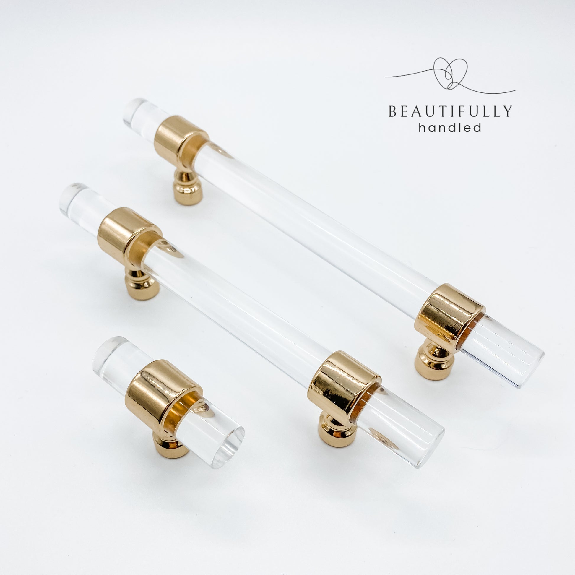 3 sizes of clear acrylic drawer handles with gold clasps on plain white background
