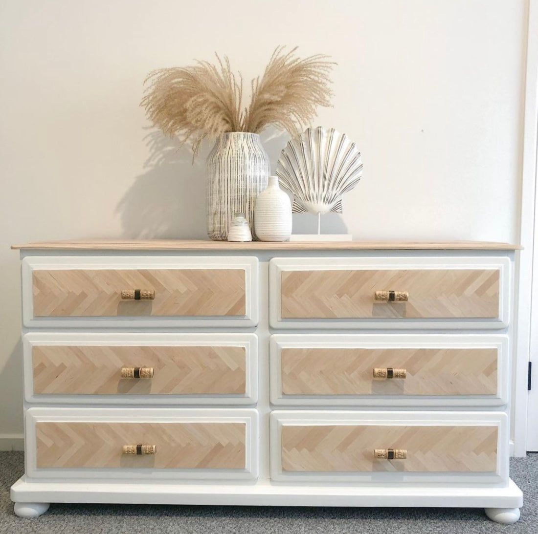 front view of rattan drawer handles on coastal style white and timber dresser against white wall