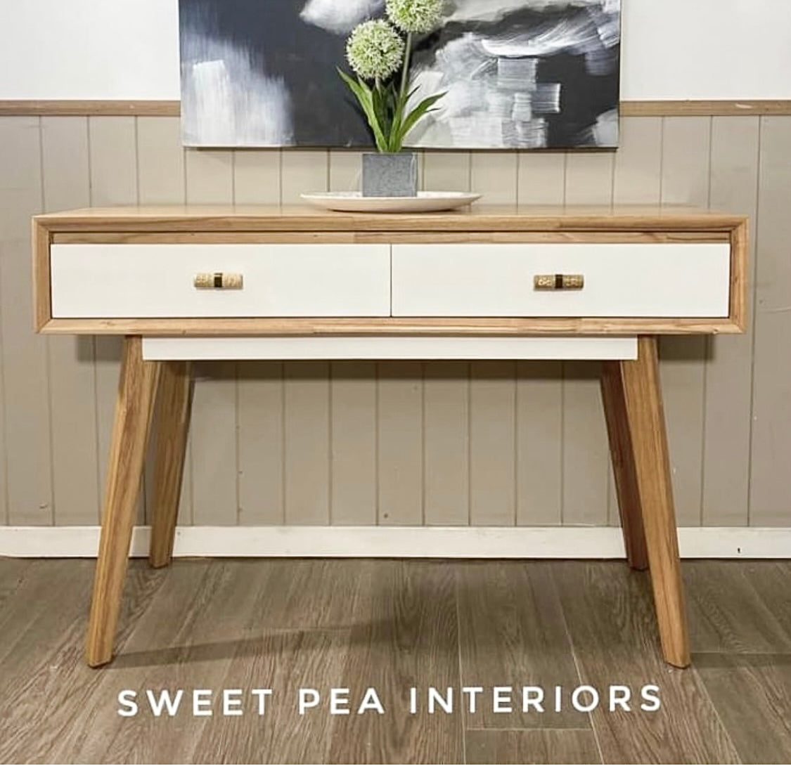 timber and white modern hall table featuring rattan drawer handles against neutral wall 